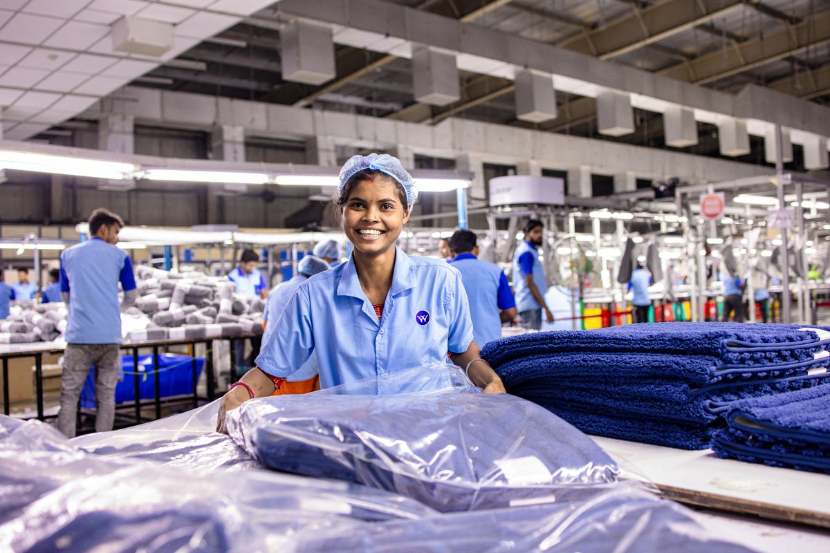 A smiling worker on a busy factory floor in India