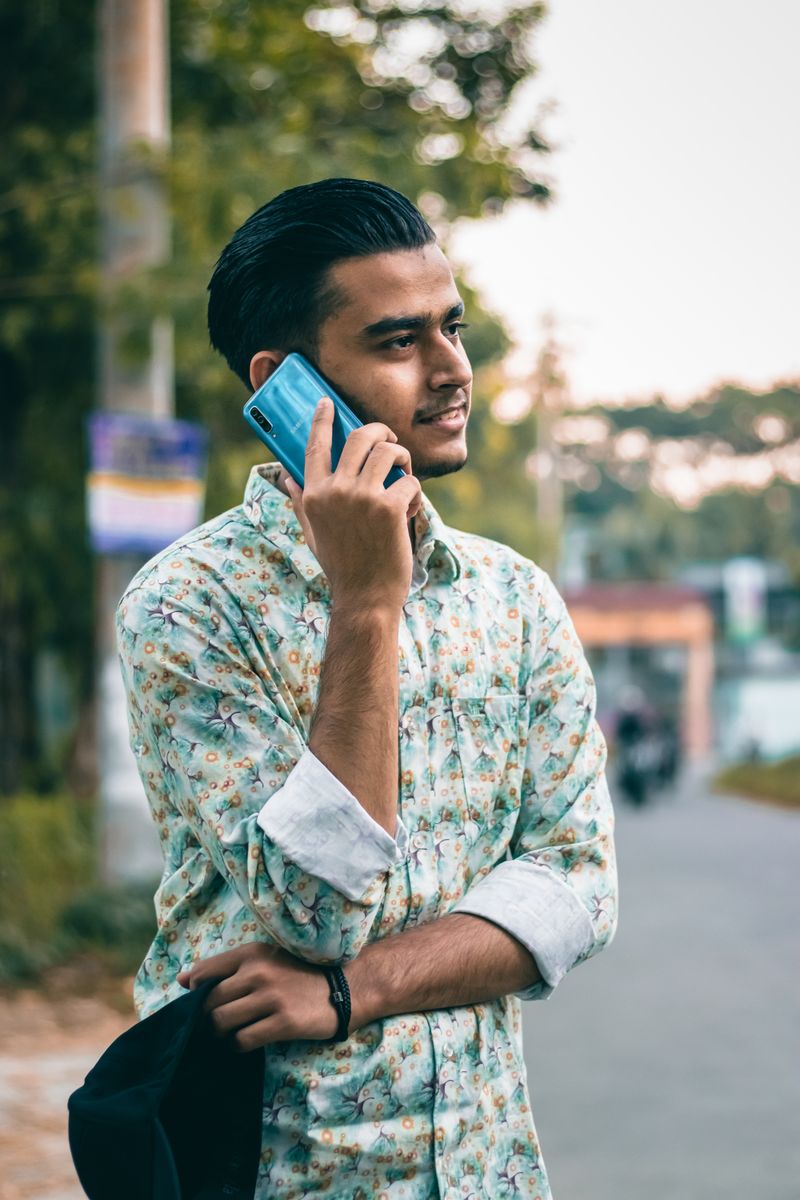 A young man smiling while talking on his phone
